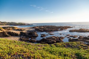 The sun sets over a rocky seashore