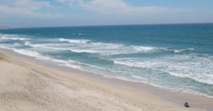 waves wash along the smooth sandy beach at half moon bay