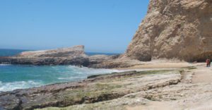 a tall cliff face and rocky outcropping extending into the ocean