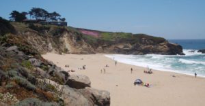waves and beach meet a cliff face