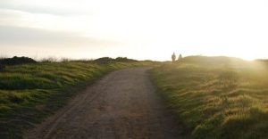 Two hikers walk along a path into the sunset