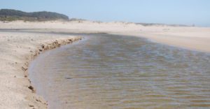 water runs along a beach towards the ocean