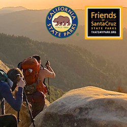 two hikers pass a rock at sunset