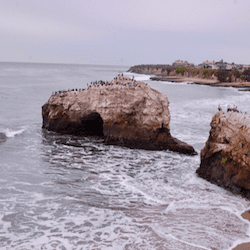 Natural bridges arch in gray ocean waters