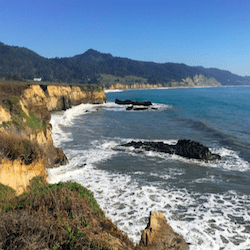 foamy ocean waves wash up at the base of cliffs