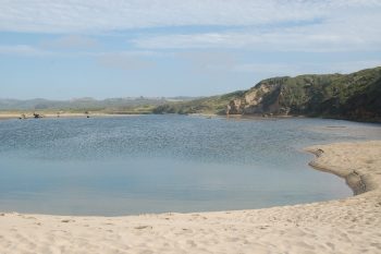 a small lagoon next to green hills