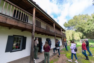 Park visitors talk on the front porch of the Castro Adobe