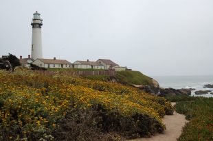 A lighthouse on a foggy day overlooking the gray-colored ocean