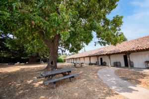 Side of the Santa Cruz Mission with a picnic table under a tree