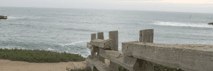 A wooden fence overlooks the ocean from a cliffside.