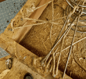 multiple strands of frayed twine are nailed and stapled to the sides of the couch