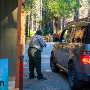 State Parks worker writes on a clipboard to the side of a visitor's car.