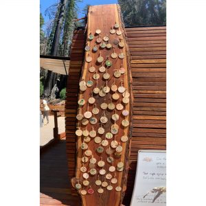 Wooden ornaments with messages written on them are pinned to a wooden plank