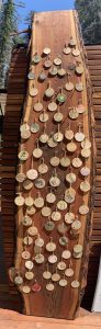 Wooden ornaments with messages written on them are pinned to a wooden plank