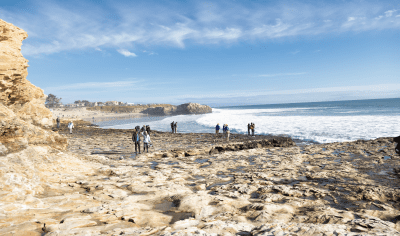 Rocky tidepools with beach-goers walking along the shore