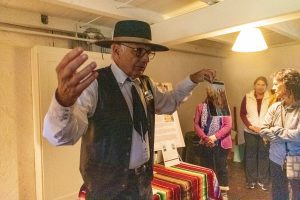 Castro Adobe tourguide holds up an image to a tour group