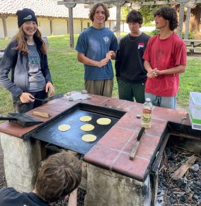 Kids standing around a wood stove at Santa Cruz Mission