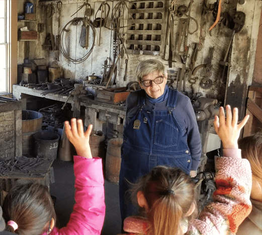 A docent speaking to kids raising their hands
